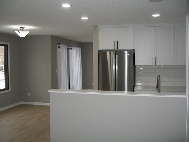 kitchen with recessed lighting, baseboards, light wood-type flooring, freestanding refrigerator, and decorative backsplash