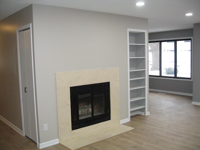 unfurnished living room featuring recessed lighting, wood finished floors, visible vents, a high end fireplace, and baseboards