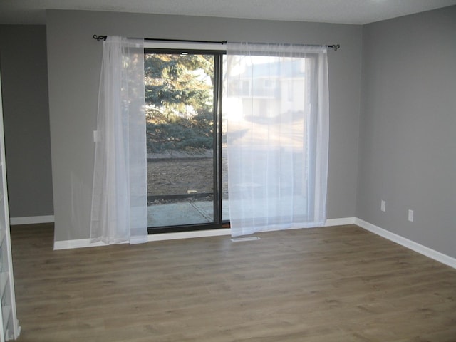 unfurnished room with baseboards and wood finished floors