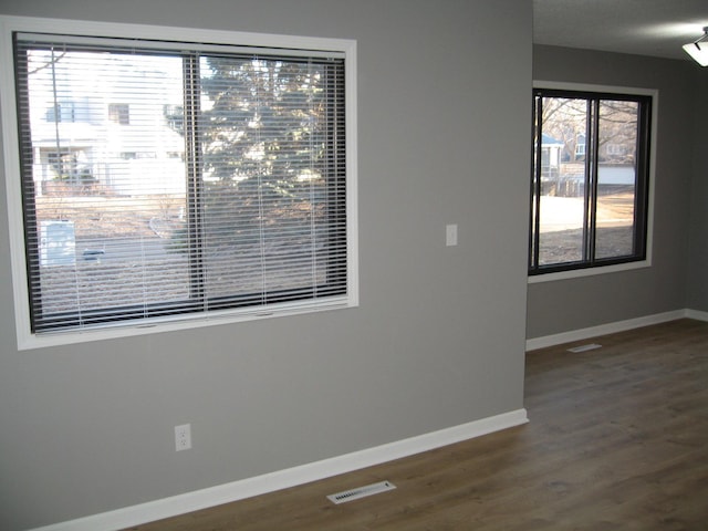 unfurnished room featuring visible vents, baseboards, and wood finished floors