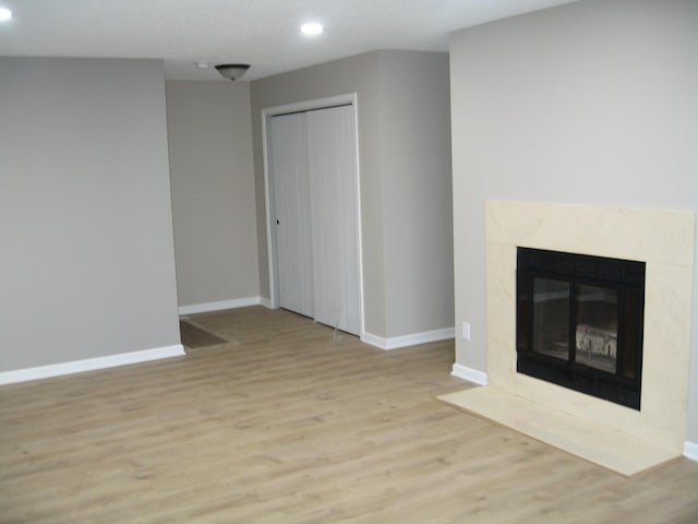 unfurnished living room with recessed lighting, wood finished floors, baseboards, and a premium fireplace