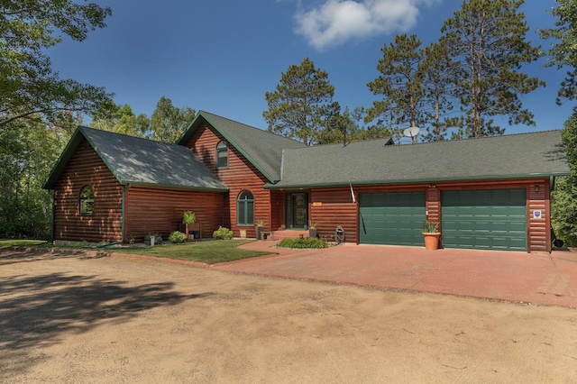 view of front of home with an attached garage, faux log siding, and concrete driveway