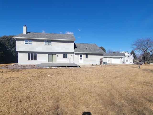 rear view of house with central AC unit, a yard, roof with shingles, a wooden deck, and a chimney