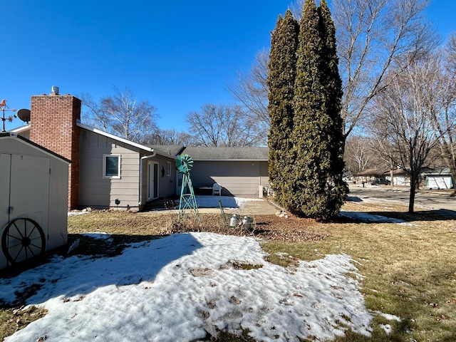 view of front of home with a storage unit, a chimney, and an outdoor structure