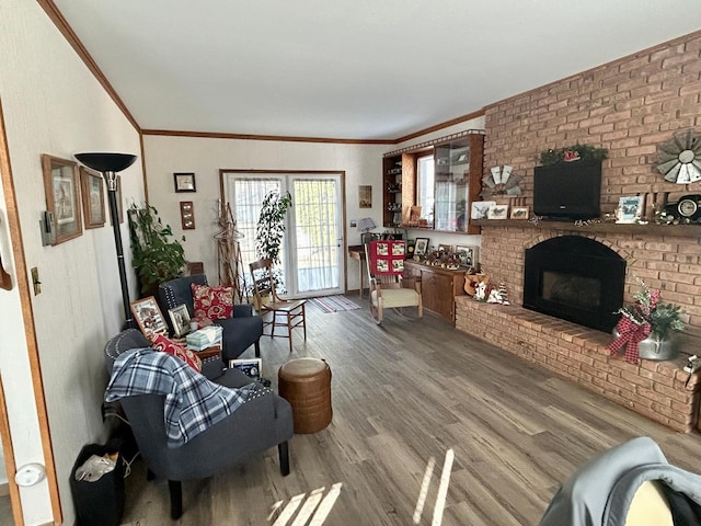 living area featuring a brick fireplace, wood finished floors, and crown molding