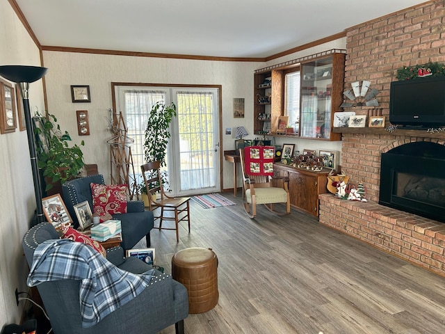 living area with a brick fireplace, crown molding, and wood finished floors