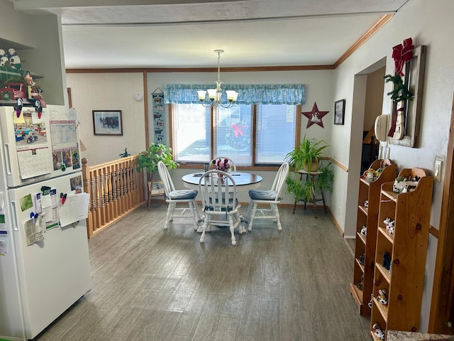 dining space with baseboards, ornamental molding, wood finished floors, and an inviting chandelier