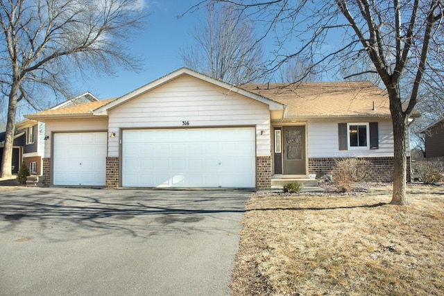 single story home with concrete driveway, an attached garage, brick siding, and roof with shingles