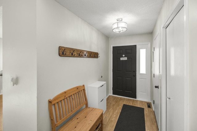 entryway with visible vents, light wood-style flooring, and a textured ceiling