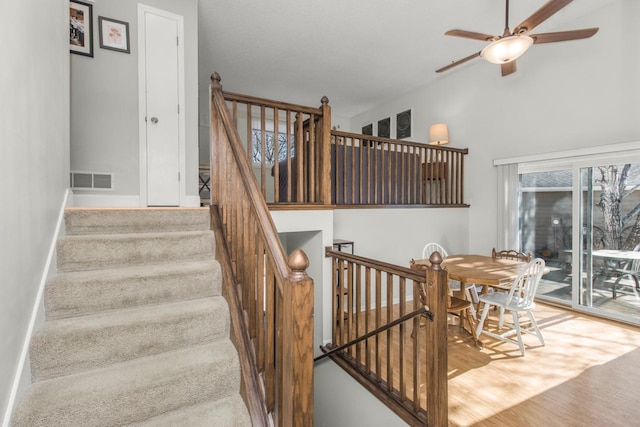 stairs with visible vents, baseboards, and ceiling fan