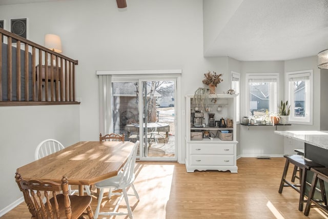 dining area featuring baseboards, light wood-style floors, and a textured ceiling