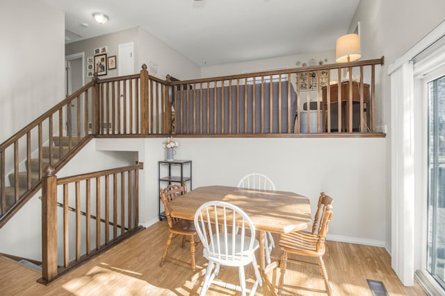 dining area with visible vents, baseboards, wood finished floors, and stairway