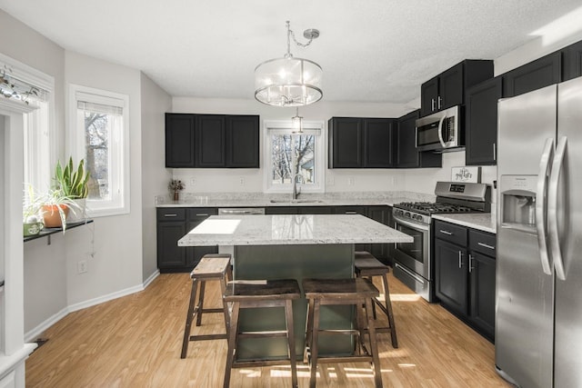 kitchen with plenty of natural light, dark cabinets, appliances with stainless steel finishes, and a sink