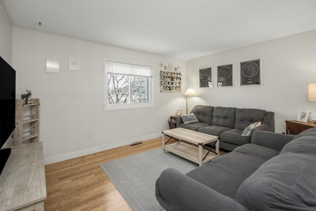 living room with visible vents, baseboards, and light wood finished floors