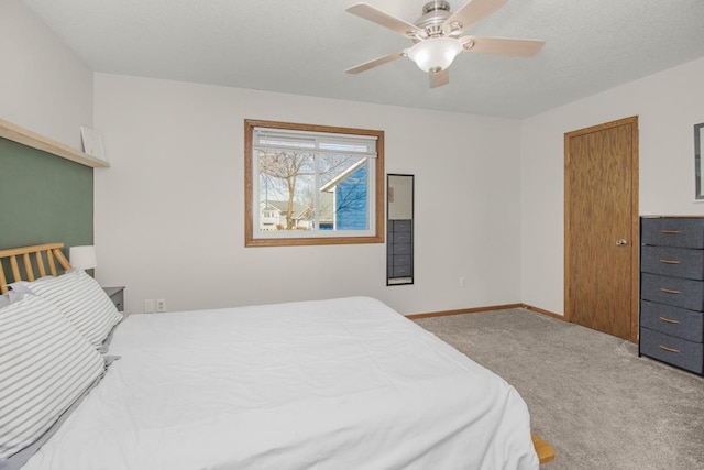 carpeted bedroom featuring a textured ceiling, a ceiling fan, and baseboards