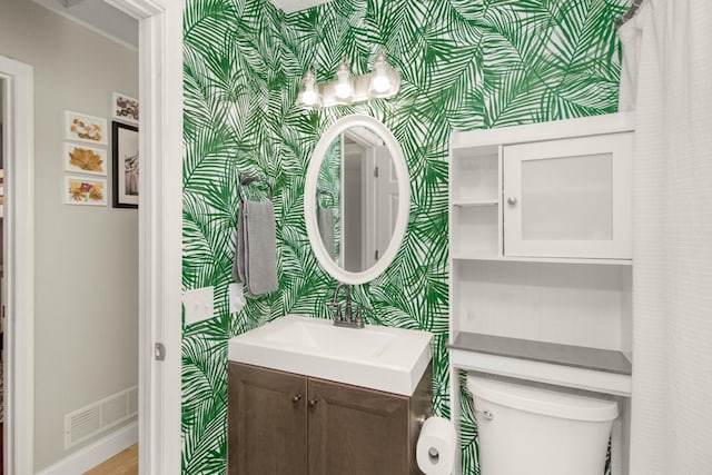 bathroom with visible vents, wallpapered walls, baseboards, toilet, and vanity