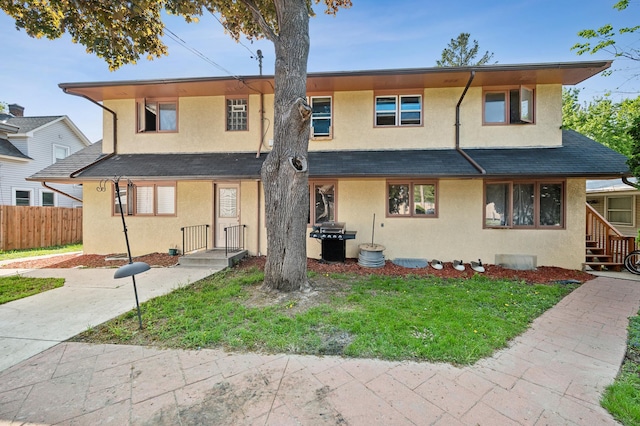 view of front facade with a front lawn, fence, and stucco siding