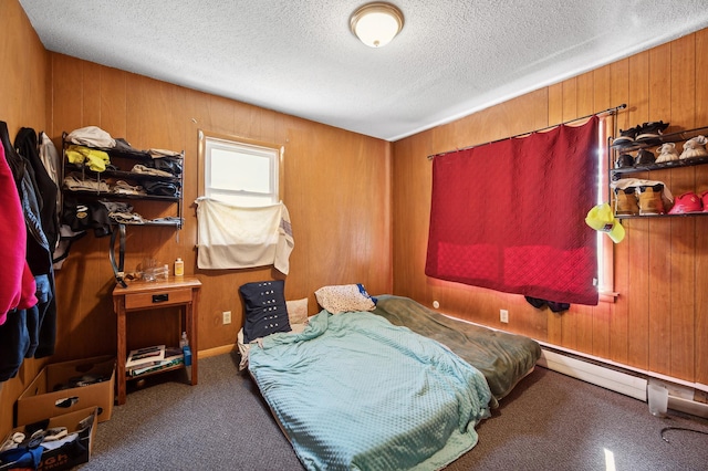 bedroom with wood walls, a textured ceiling, and carpet flooring