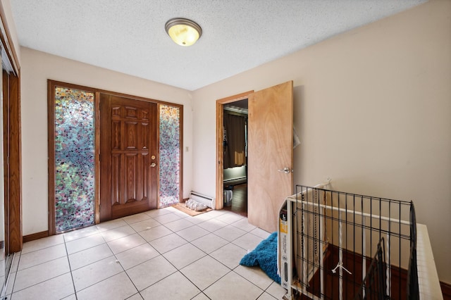 foyer featuring light tile patterned floors, baseboards, a baseboard heating unit, and a textured ceiling