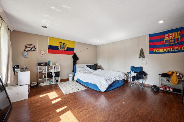 bedroom with a textured ceiling, wood finished floors, and baseboards