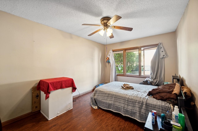 bedroom with ceiling fan, a textured ceiling, baseboards, and wood finished floors