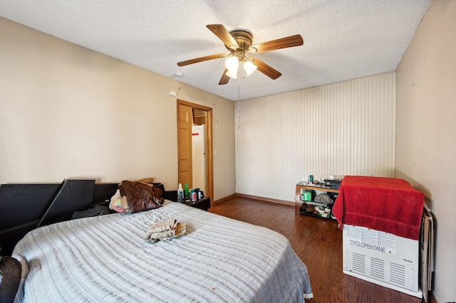 bedroom with a textured ceiling, wood finished floors, and a ceiling fan