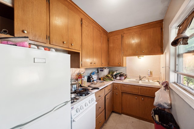 kitchen featuring white appliances, a sink, light countertops, light floors, and brown cabinetry