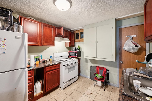 kitchen featuring reddish brown cabinets, white appliances, light tile patterned floors, a textured ceiling, and under cabinet range hood