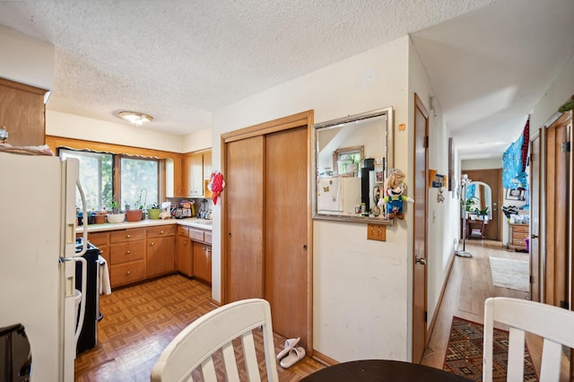 kitchen featuring a textured ceiling, light countertops, stainless steel range with electric stovetop, and freestanding refrigerator