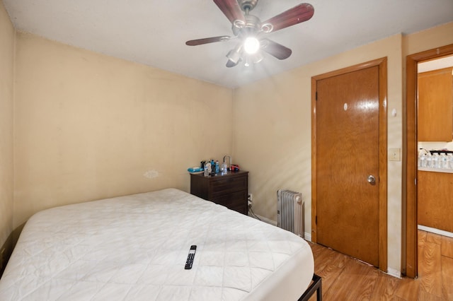 bedroom featuring a ceiling fan, radiator heating unit, and wood finished floors