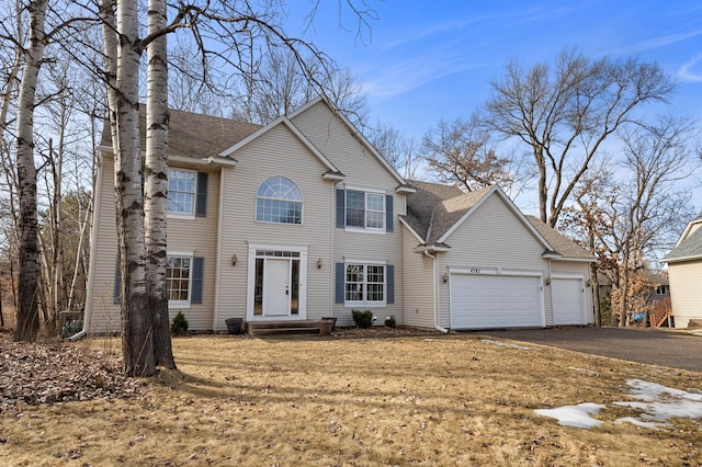 colonial inspired home with an attached garage, driveway, and roof with shingles