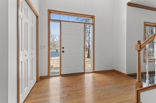 entryway featuring baseboards, stairway, and light wood finished floors