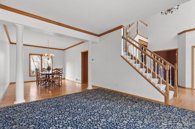 dining room featuring decorative columns, ornamental molding, wood finished floors, baseboards, and stairs