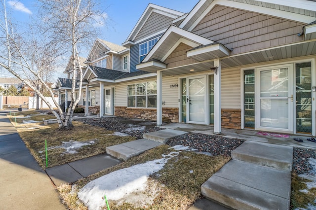 doorway to property featuring stone siding and fence