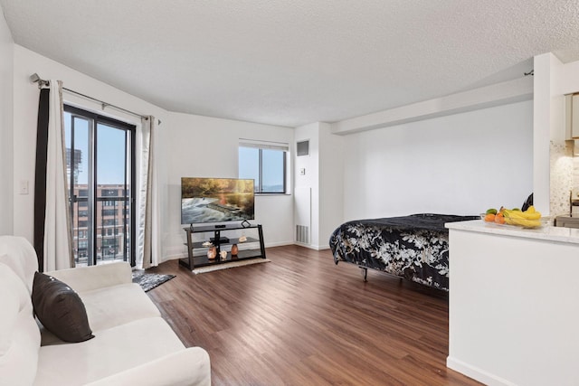 bedroom featuring visible vents, baseboards, a textured ceiling, and wood finished floors