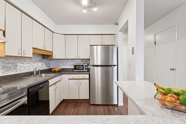 kitchen featuring a sink, dark wood-type flooring, decorative backsplash, and stainless steel appliances