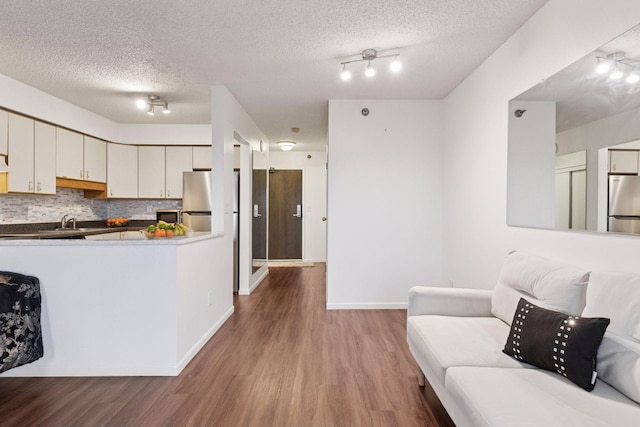 kitchen with tasteful backsplash, a textured ceiling, freestanding refrigerator, and wood finished floors