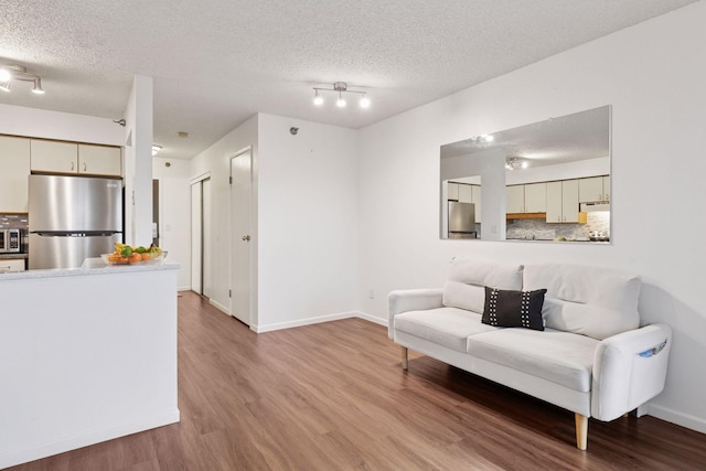 living area with wood finished floors, baseboards, and a textured ceiling