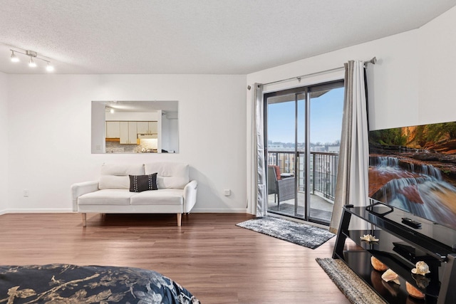 interior space with a textured ceiling, baseboards, and wood finished floors