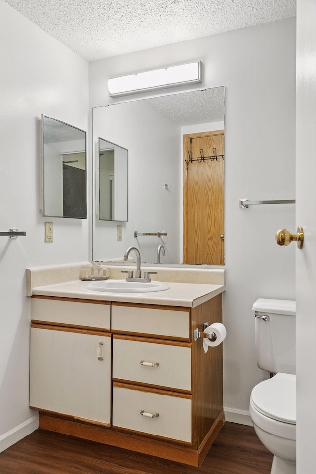 bathroom featuring a textured ceiling, toilet, vanity, and wood finished floors