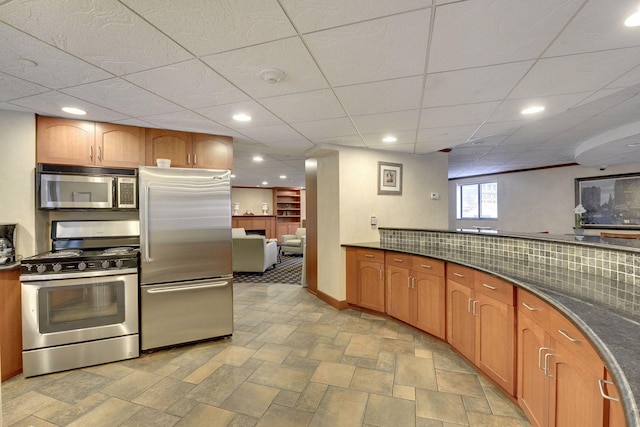 kitchen featuring recessed lighting, stone finish flooring, baseboards, and appliances with stainless steel finishes