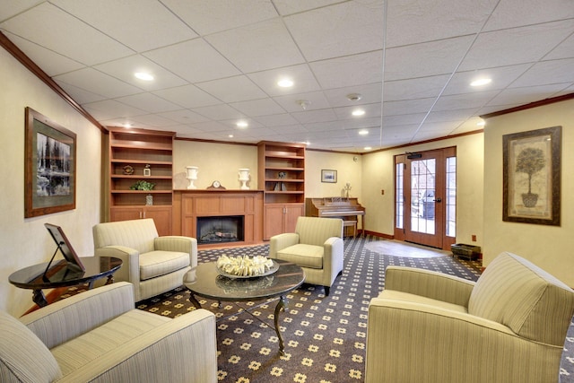 living room with built in shelves, carpet flooring, a fireplace, crown molding, and baseboards