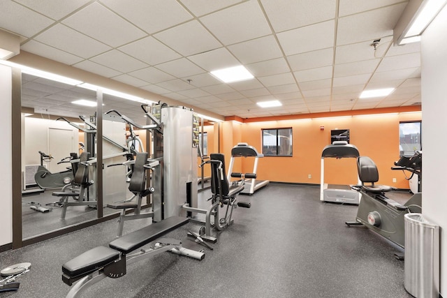 gym featuring a drop ceiling and baseboards