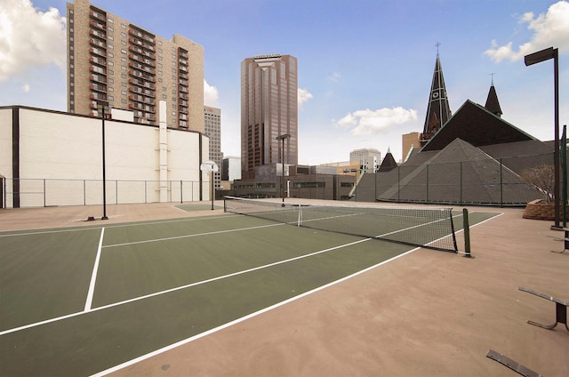 view of sport court featuring a view of city and fence