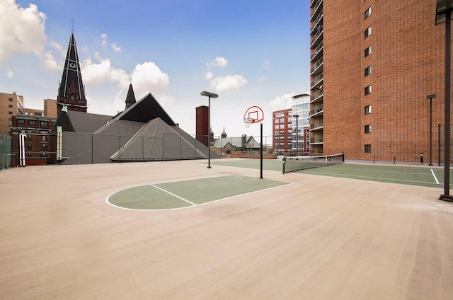 view of basketball court featuring a tennis court, community basketball court, and fence