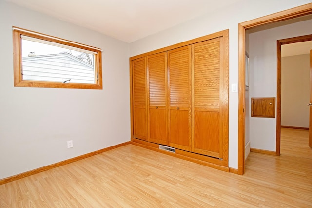 unfurnished bedroom featuring light wood finished floors, baseboards, visible vents, and a closet