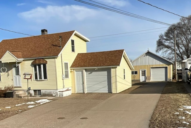 view of front of home featuring a chimney, a shingled roof, an outbuilding, and a garage