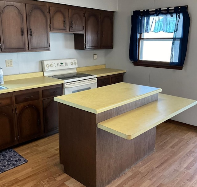 kitchen featuring dark brown cabinets, light countertops, electric stove, and light wood-style floors