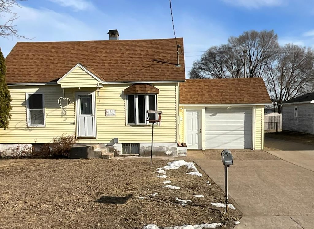 view of front of home with entry steps, roof with shingles, concrete driveway, an attached garage, and a chimney