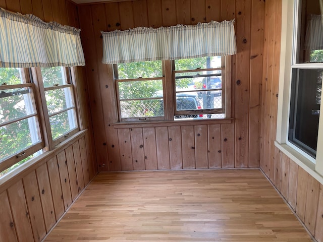 spare room with a wealth of natural light, wood walls, and light wood-style flooring